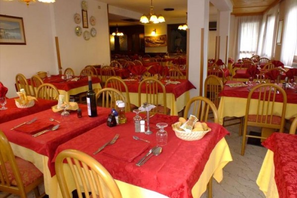 Restaurace s dřevěnými židlemi a stoly s červenými ubrusy.
