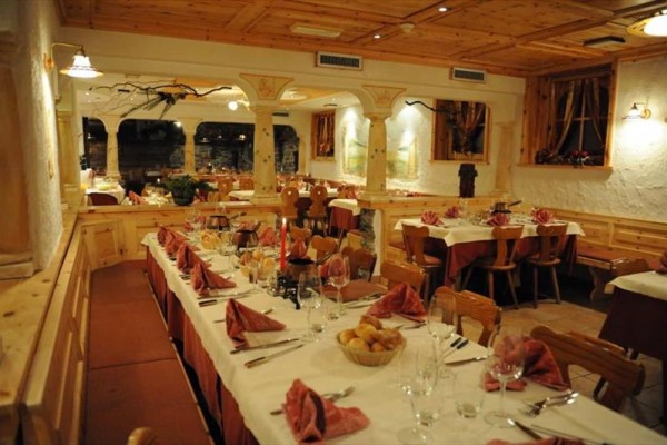 Rustikální restaurace s dřevěnými stoly krásně prostřenými pro hosty.  