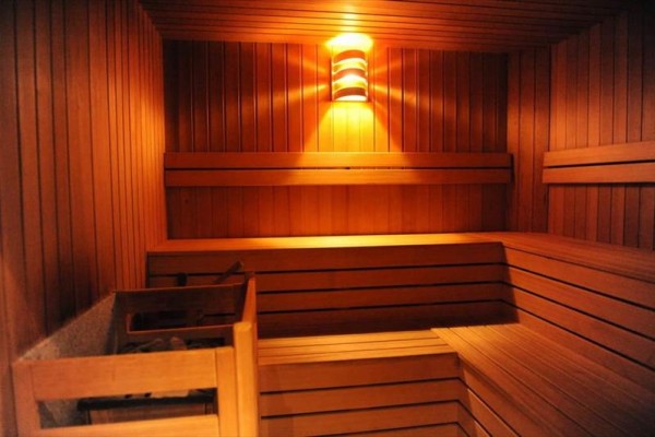 Dřevěná sauna s lavicemi a jemným osvětlením na stěně.