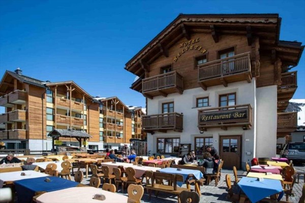 Dřevěný hotel s restaurací a venkovním posezením.