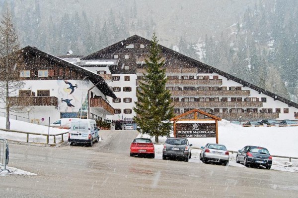 Horský hotel s parkovištěm pokrytým sněhem.