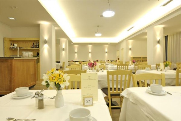 Světlá restaurace s prostřenými stoly a dekoracemi květin.