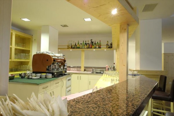 Moderní bar s mramorovým pultem a kavovarem na vzdušném, světlem osvětleném místě.