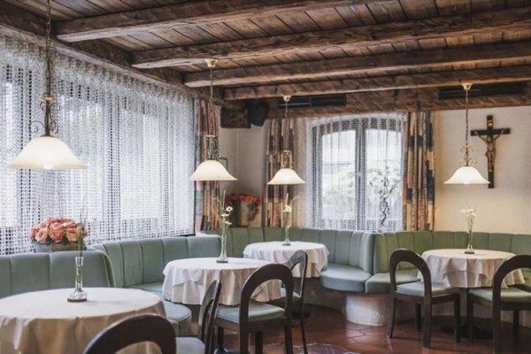 Uvnitř restaurace se dřevěným stropem a zelenými pohovkami kolem kulatých stolů.