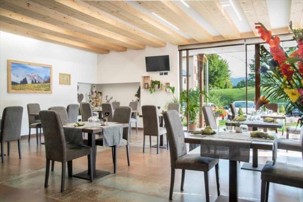 Elegantní restaurace s prosklenými dveřmi vedoucími ven do zeleně.