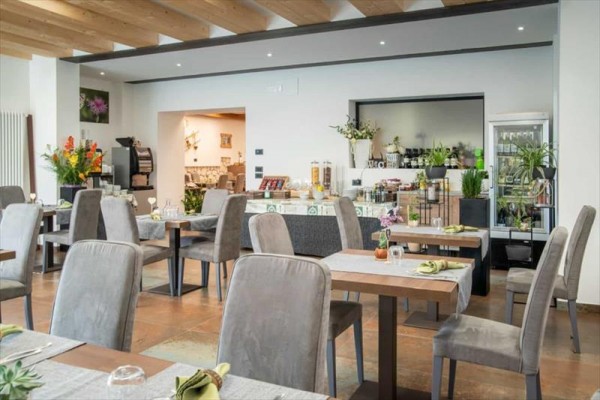Moderní restaurace s šedými židlemi a dřevěným stropem.