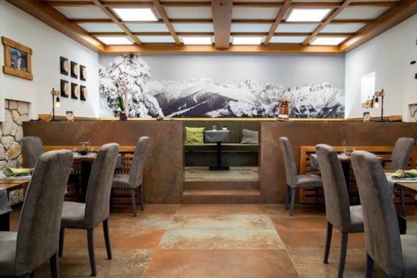 Restaurace s dřevěným stropem a fotografií zasněžených hor na stěně.