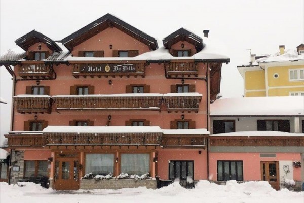 Růžový hotel s dřevěnými balkony pokrytými sněhem.