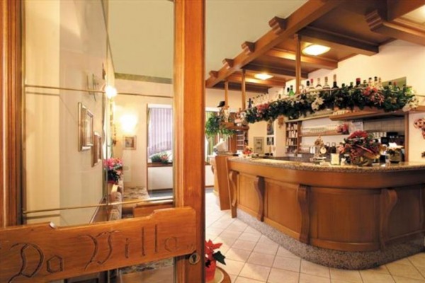 Interiér restaurace s dřevěným barem a květinovou dekorací.  