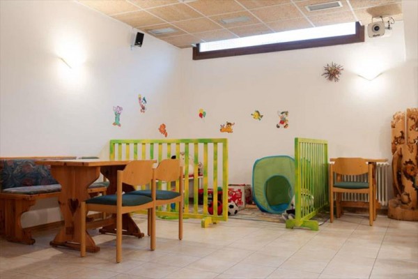 Dětský koutek s hračkami a stoly ve vyzdobené místnosti.