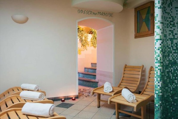 Relaxační místnost se dvěma lehátky a složenými ručníky u vchodu do místnosti s názvem „Wasser Paradise“.