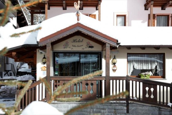Vstup do zasněženého hotelu s dřevěným zábradlím.
