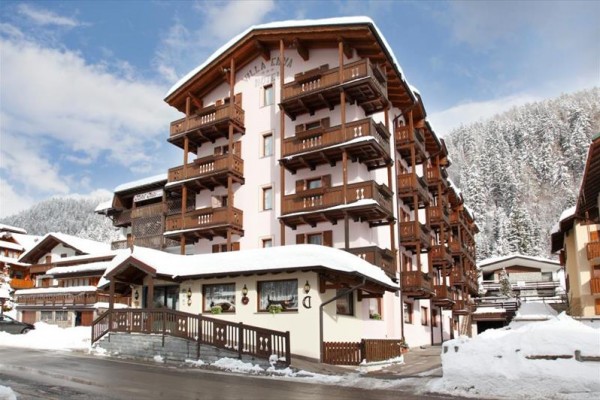 Horské apartmánové budovy se zasněženou krajinou.