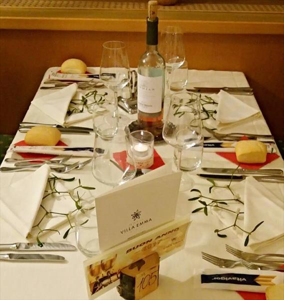 Elegantně prostřený stůl s vínem, sklenicemi, svíčkou a dekorací.