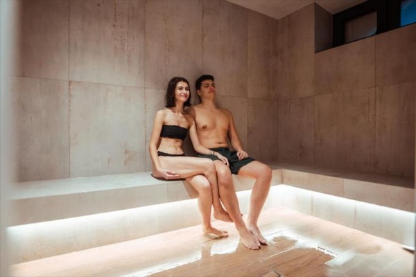Mladý pár sedí ve wellness sauně.