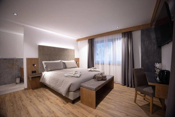 Moderní ložnice s dřevěnou podlahou a velkou postelí.