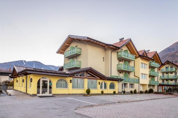 Žlutá budova hotelu s balkony v horské oblasti.