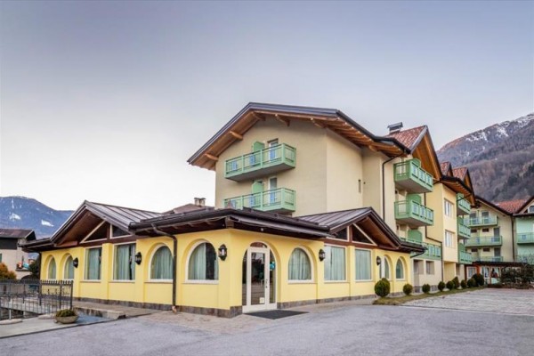 Žlutá budova s balkonem v horském prostředí.  