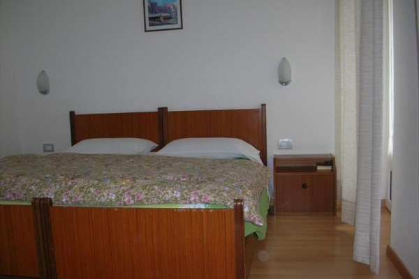 Ložnice s manželskou postelí, nočním stolkem a závěsem.