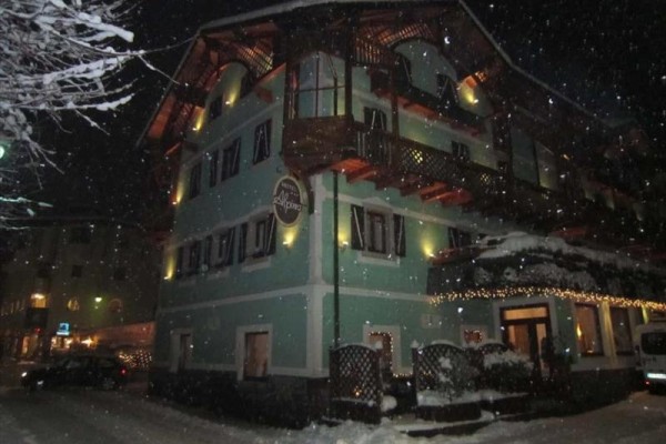 Zasněžený hotel ve tmě s nasvícenou fasádou.