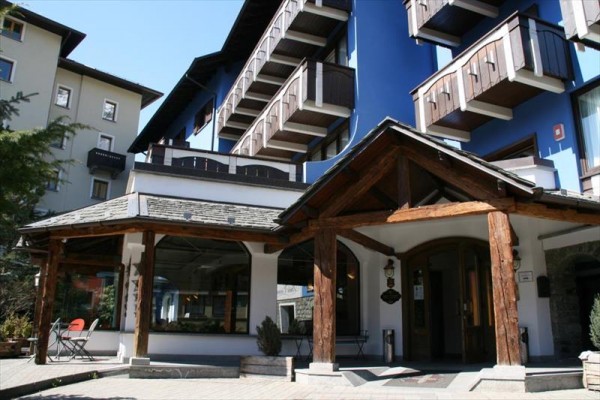 Vchod do horského hotelu s dřevěnými detaily a balkony.