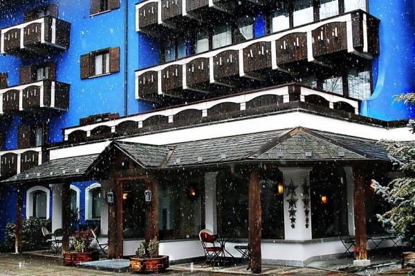 Modrý hotel s dřevěnými balkony během sněžení.