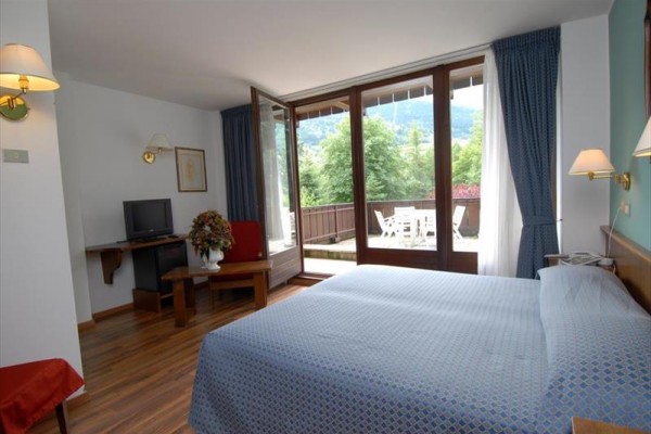 Modrá budova hotelu se zasněženým okolím a balkony s rostlinami.