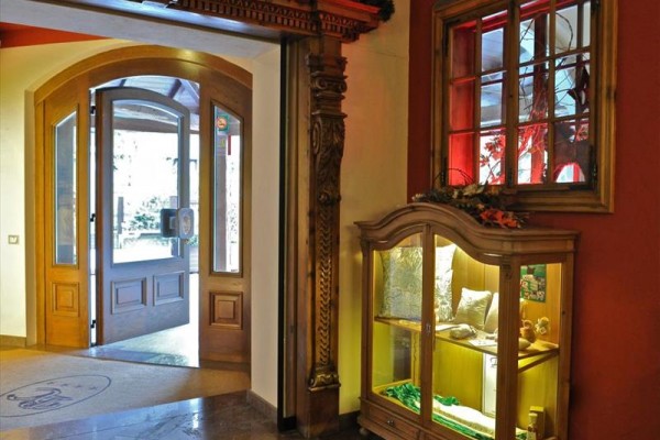 Modrý hotel s dřevěnými balkonky ozdobenými květinami ve sněhovém prostředí.