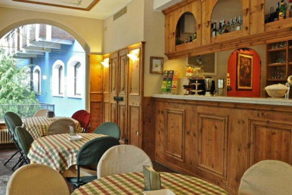 Zasněžený hotel s modrou fasádou a balkony při večerním osvětlení.