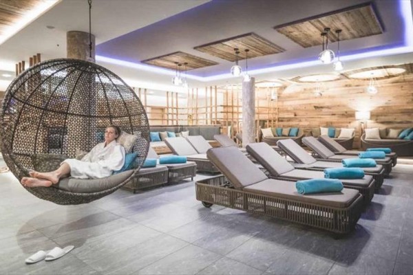 Osoba v županu relaxuje na závěsném křesle v moderním wellness centru.