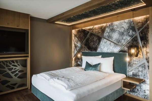 Moderní ložnice s elegantním dvoulůžkem a designovou tapetou na stěně.