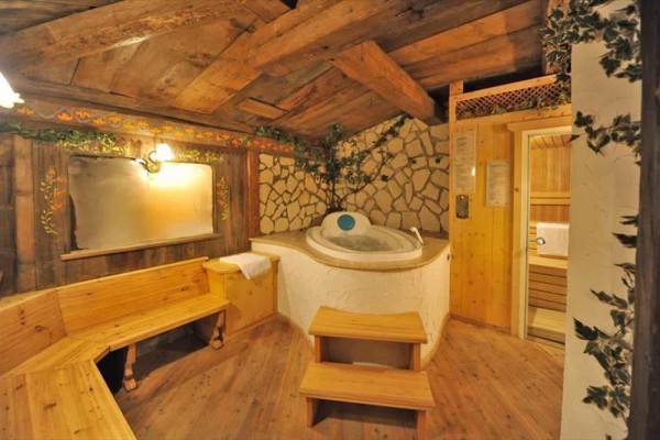 Útulná dřevěná sauna s vířivkou a posezením v rustikálním stylu.  