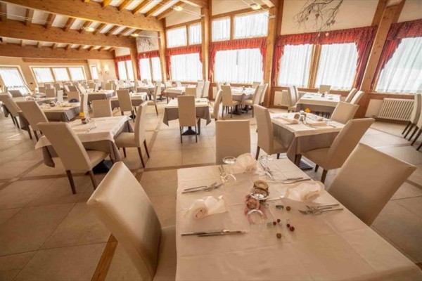 Prostorná restaurace s bílými ubrusy a pohodlnými židlemi.