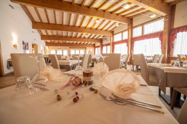 Restaurace s prostřenými stoly a dřevěným stropem.