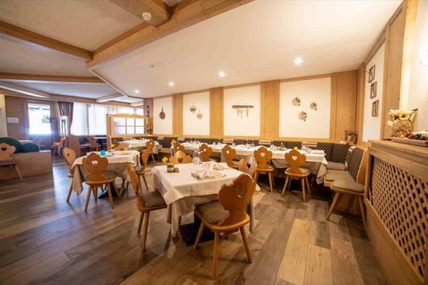 Restaurace s dřevěným obložením a stolky s bílými ubrusy.