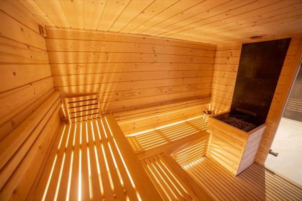 Dřevěná sauna s lavicemi a kamny.
