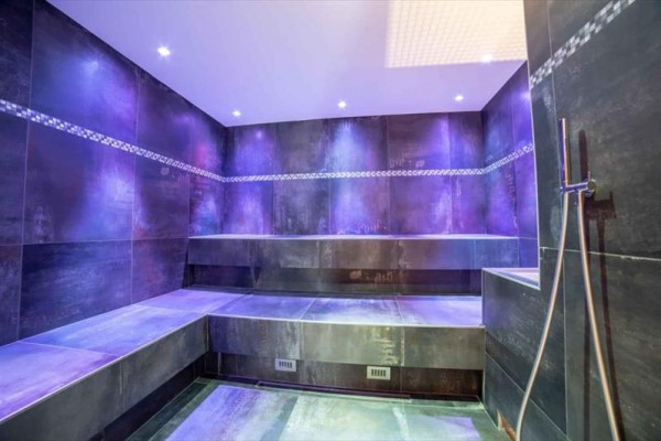 Moderní parní sauna s fialovým osvětlením.