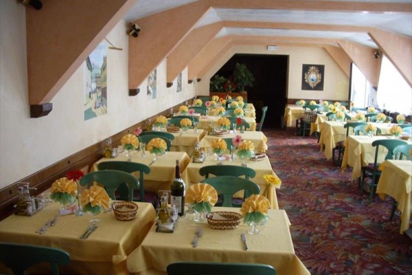 Restaurace s nažehlenými ubrusy a květinovou výzdobou na stolech.