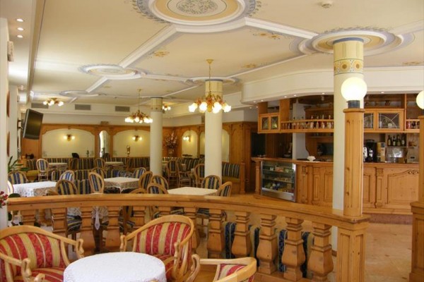 Interiér restaurace s dřevěným nábytkem a zdobeným stropem.  