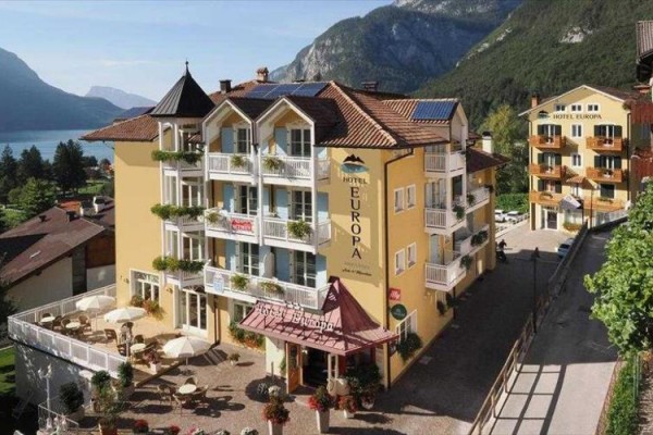 Hotel u jezera s horami v pozadí.