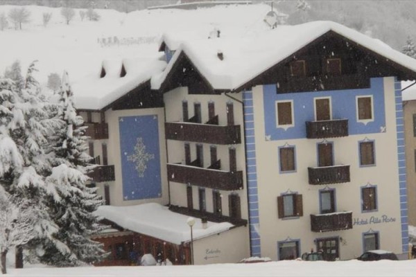 Hotel v zasněžené zimní krajině se zdobením na fasádě.
