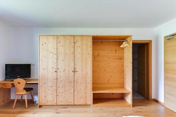 Dřevěný nábytek v pokoji s šatní skříní, psacím stolem a televizí.