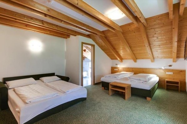 Dvoulůžkový pokoj s dřevěnými stropy a dvěma manželskými postelemi.