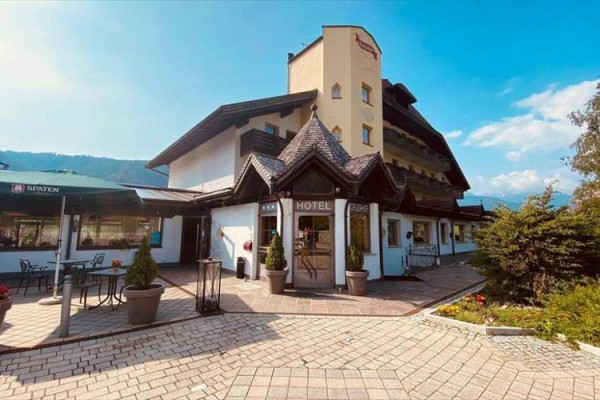 Hotel s dřevěnými prvky a terasou ve slunečném prostředí.