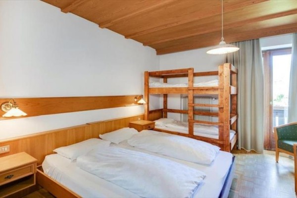 Pokoj s manželskou postelí, palandou a balkonovými dveřmi.