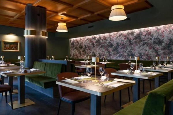 Elegantní restaurace s čalouněnými lavicemi a obrazy na stěnách.