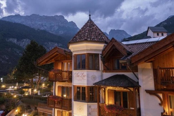 Hotel ve večerním osvětlení s horami v pozadí.