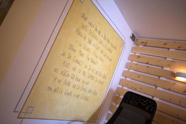 Zeď pokrytá dřevěným obložením a žlutou plochou s nápisem v cizím jazyce.