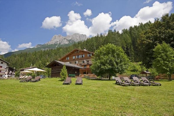 Horské letovisko obklopené lesy s lehátky na trávníku.