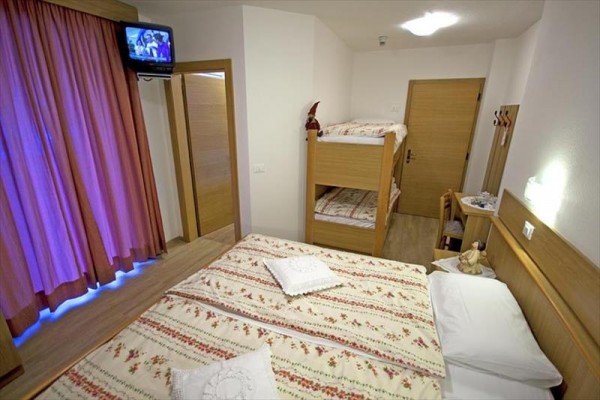 Pokoj s manželskou postelí, palandou, televizí a závěsy.